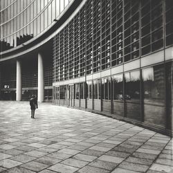 Rear view of woman walking on walkway at palazzo lombardia