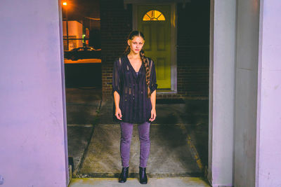 Portrait of smiling woman standing against illuminated wall