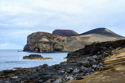 Rock formations by sea against sky