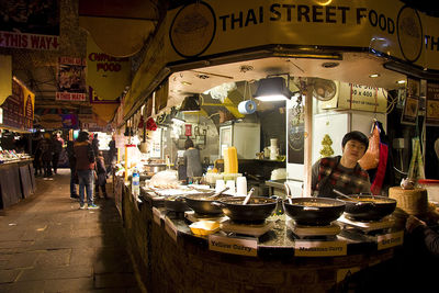 People at illuminated market stall at night