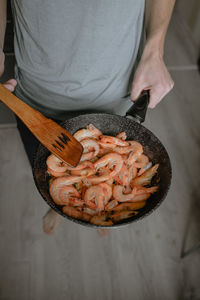 Cooking shrimp at home, fried in a pan, holding, large fresh shrimp in a pan