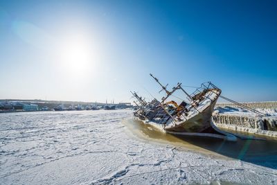 Abandoned ship in winter against sky