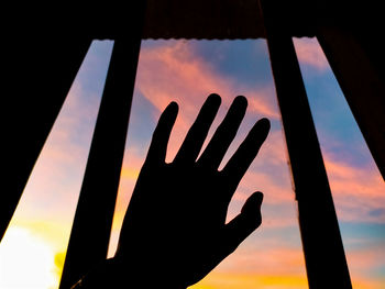 Low angle view of silhouette hand against sky during sunset