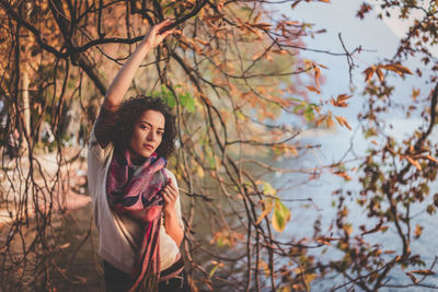 Portrait of beautiful young woman standing against tree