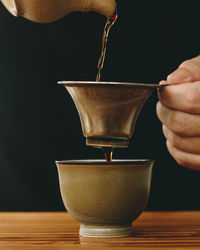 Close-up of hand pouring coffee in cup