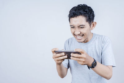 Young man using mobile phone against white background