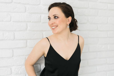 Portrait of young woman standing against brick wall