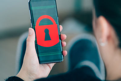 Cropped hand of mid adult woman holding mobile phone