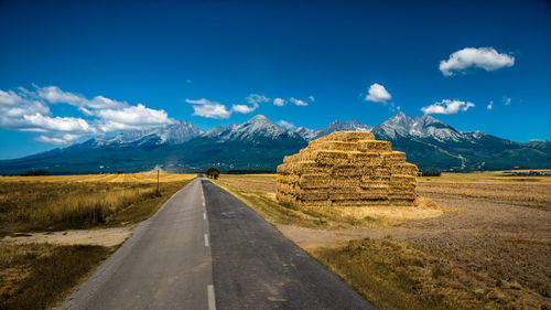 Road amidst field against sky