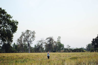 Rear view of man standing in field against clear sky