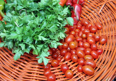 Parsley and cherry tomatoes in orange knitted basket