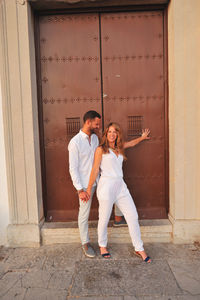Happy young couple standing against closed door of historic building