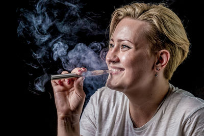Close-up of man smoking cigarette against black background