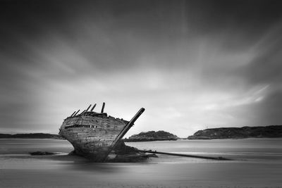 Abandoned boat in sea against sky