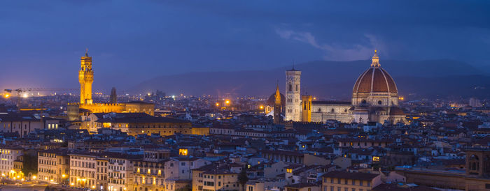 Illuminated buildings in city against sky