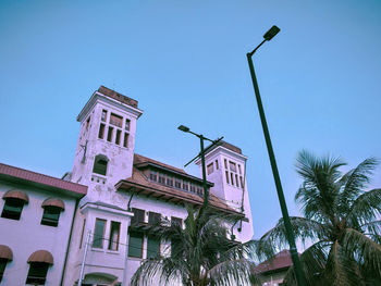 Low angle view of palm trees and building against sky