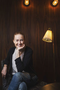 Portrait of happy businesswoman sitting on chair in office lobby