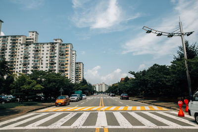 Cars on street amidst trees against sky