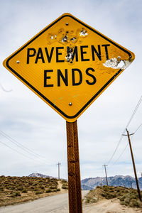 Low angle view of road sign against sky pavement ends