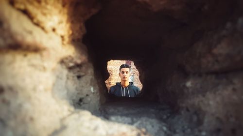 Man looking at camera through a hole in the wall