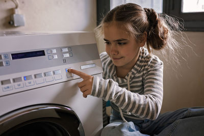 Teenage girl using common laundry to save resources and money. sustainability and environment care