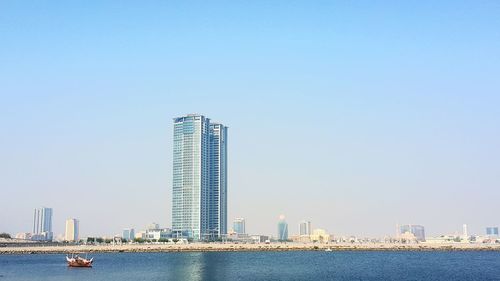 Scenic view of river by buildings against clear sky