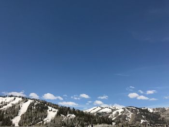 Low angle view of snowcapped mountain against blue sky