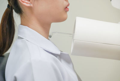 Close-up of woman standing against white wall