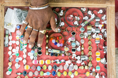 Cropped hand of man with colorful rings in container
