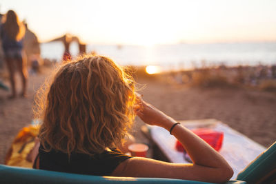 Rear view of woman sitting at beach