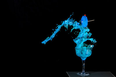 Close-up of blue drink splashing against black background