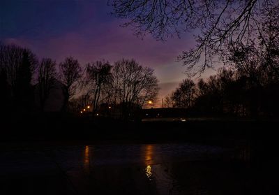 Silhouette trees by lake against sky at sunset