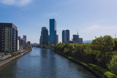 River amidst buildings in city against sky