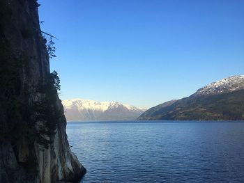 Scenic view of lake and mountains against clear blue sky