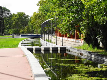 Scenic view of bridge over grass by trees against sky