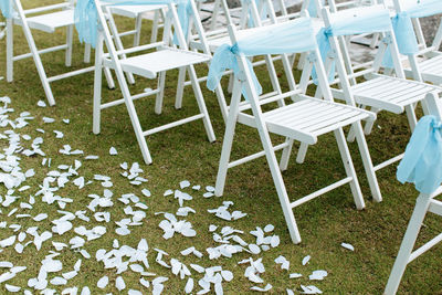 View of white chairs with blue ribbons during a garden wedding ceremony