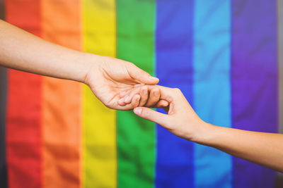 Close-up of hand holding multi colored glass against blurred background