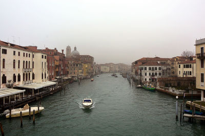 Canal in city against clear sky