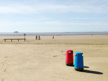 Bins on beach against blue sky