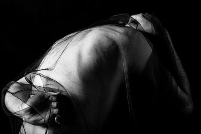 Close-up portrait of young woman against black background