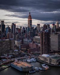 Aerial view of buildings in city against cloudy sky