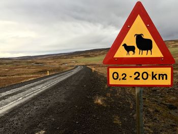 Road sign against cloudy sky