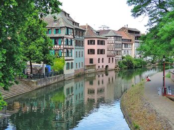 Canal by buildings in city against sky