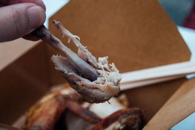 Cropped hand of person holding deep-fried chicken drumstick 