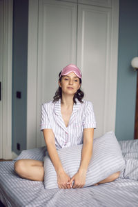 Woman in pajamas and with a sleep mask on the bed in the bedroom