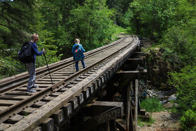 People on railroad tracks amidst trees