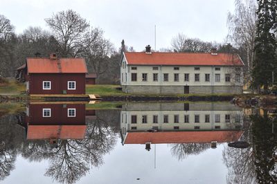 Houses by lake against sky during fall