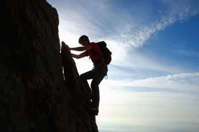 Low angle view of man on climbing on rocky mountain against sky