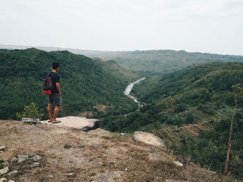 Man standing on cliff against sky