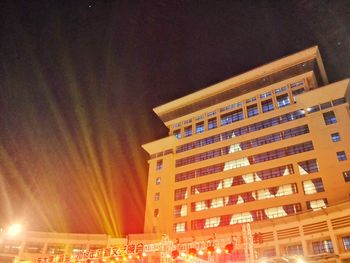 Low angle view of illuminated buildings against sky at night